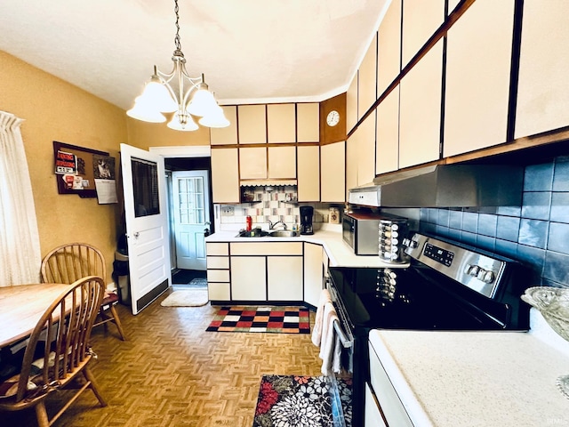 kitchen with a sink, light countertops, stainless steel electric range oven, tasteful backsplash, and an inviting chandelier