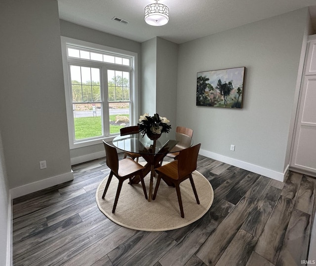 dining area featuring dark wood finished floors, visible vents, and baseboards