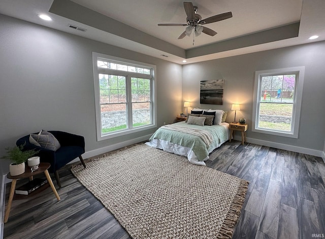 bedroom featuring wood finished floors, a raised ceiling, visible vents, and baseboards