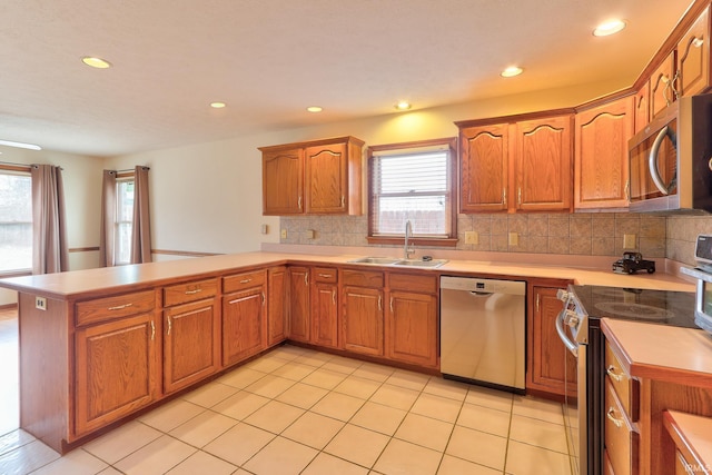 kitchen featuring appliances with stainless steel finishes, light countertops, a sink, and a peninsula