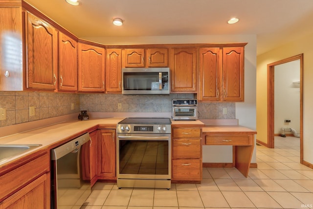 kitchen featuring stainless steel appliances, brown cabinets, light countertops, and decorative backsplash