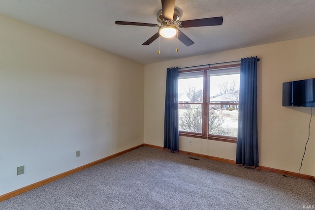 carpeted spare room featuring a ceiling fan, visible vents, and baseboards