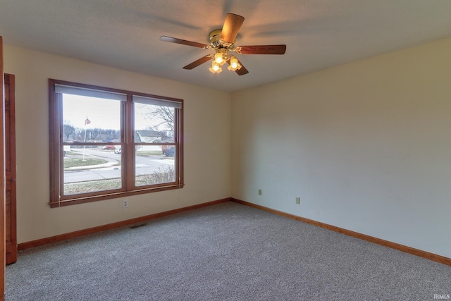 empty room with carpet floors, visible vents, baseboards, and a ceiling fan