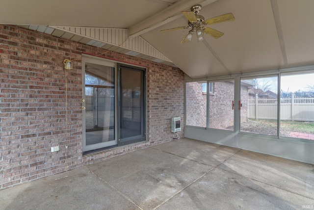 unfurnished sunroom featuring vaulted ceiling with beams, heating unit, and ceiling fan