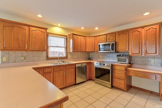 kitchen featuring brown cabinetry, backsplash, stainless steel appliances, and a sink