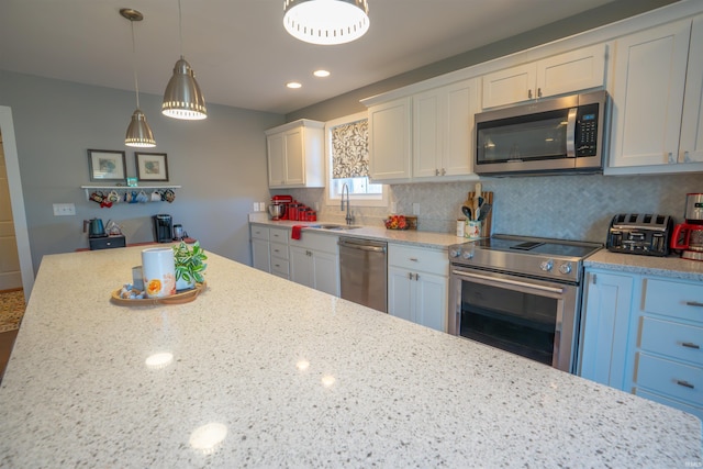 kitchen featuring pendant lighting, stainless steel appliances, decorative backsplash, white cabinetry, and a sink