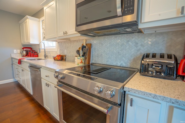 kitchen with a sink, white cabinetry, appliances with stainless steel finishes, dark wood-style floors, and tasteful backsplash