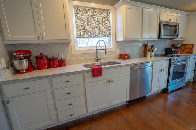 kitchen featuring stainless steel appliances, dark wood-type flooring, a sink, white cabinetry, and decorative backsplash