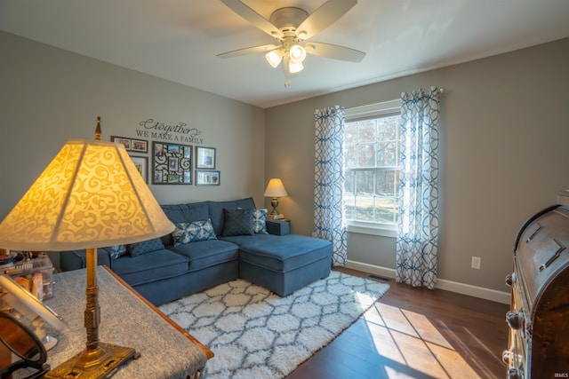 living area featuring ceiling fan, wood finished floors, visible vents, and baseboards