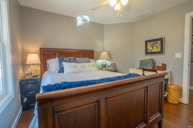 bedroom with dark wood-type flooring, visible vents, ceiling fan, and baseboards