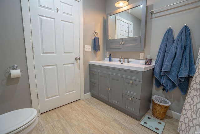 bathroom with toilet, baseboards, and vanity