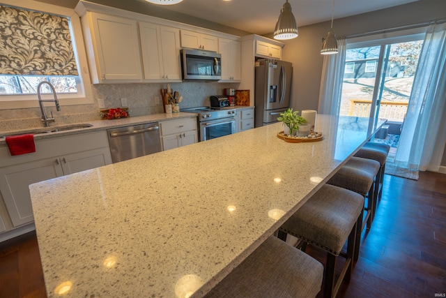 kitchen featuring appliances with stainless steel finishes, a healthy amount of sunlight, a sink, and a kitchen bar