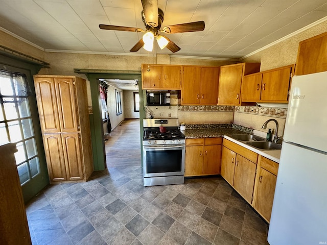 kitchen with black microwave, a sink, stainless steel gas range, a wealth of natural light, and freestanding refrigerator