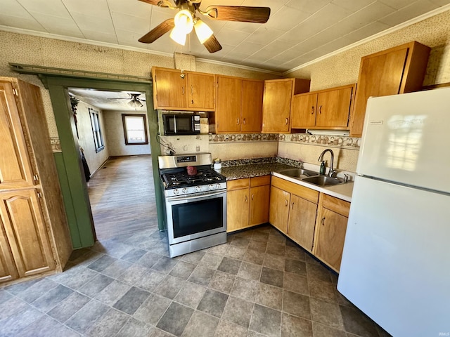 kitchen with black microwave, a sink, freestanding refrigerator, gas stove, and wallpapered walls