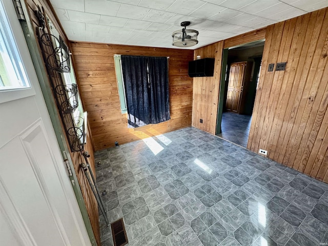 spare room with visible vents, wooden walls, and tile patterned floors