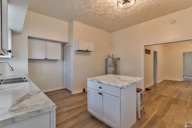 kitchen with a kitchen breakfast bar, white cabinets, a sink, and wood finished floors