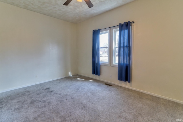 carpeted spare room featuring ceiling fan, a textured ceiling, visible vents, and baseboards