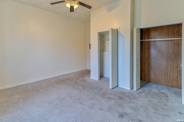 unfurnished bedroom featuring multiple closets, lofted ceiling, a ceiling fan, carpet flooring, and baseboards