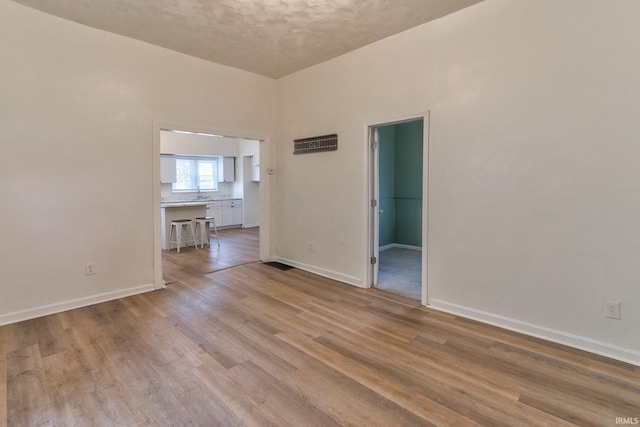 spare room with baseboards and wood finished floors