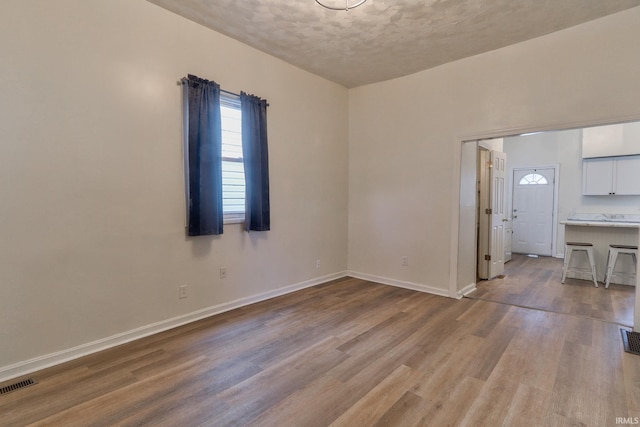 empty room with baseboards, visible vents, and wood finished floors