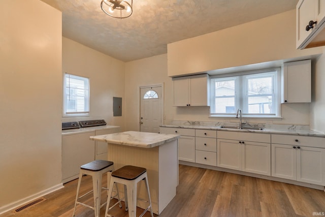 kitchen with electric panel, visible vents, a center island, separate washer and dryer, and a sink