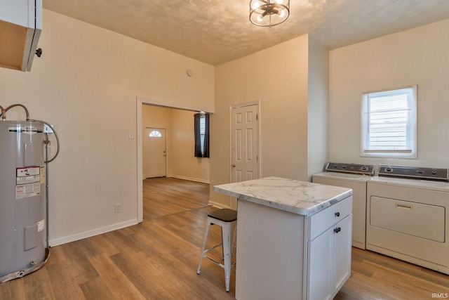 kitchen with light wood-type flooring, a center island, water heater, and independent washer and dryer