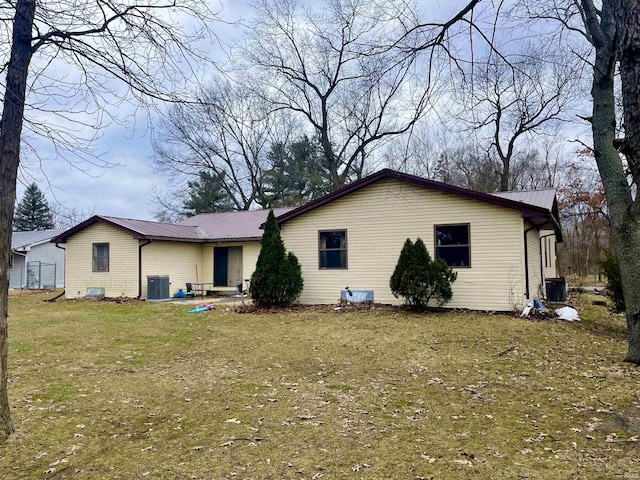 rear view of property with metal roof, a lawn, and central air condition unit