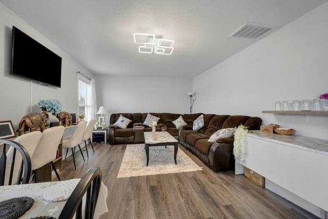 living area with a textured ceiling, wood finished floors, and visible vents