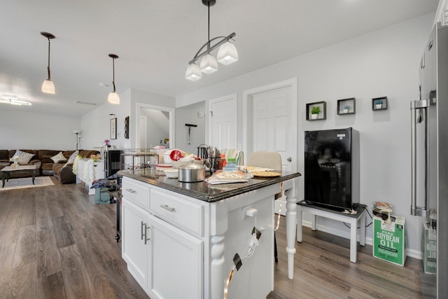 kitchen featuring white cabinets, dark wood finished floors, dark countertops, open floor plan, and hanging light fixtures