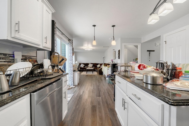 kitchen featuring wood finished floors, white cabinets, hanging light fixtures, stainless steel dishwasher, and decorative backsplash