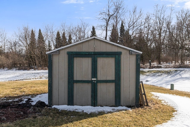 snow covered structure with an outdoor structure and a shed