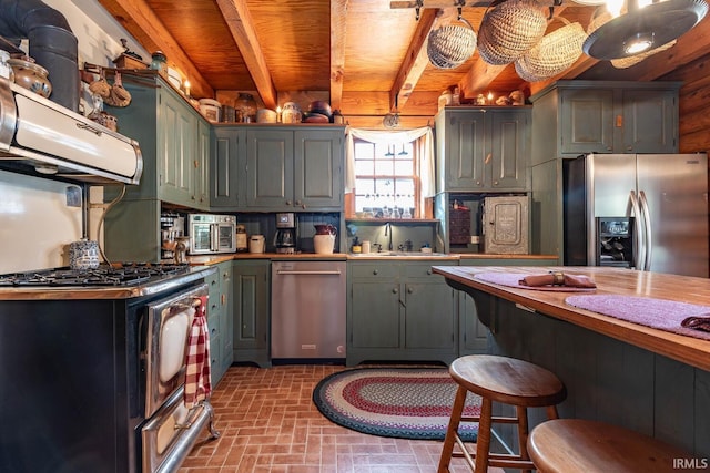 kitchen with brick floor, green cabinets, stainless steel appliances, and a sink