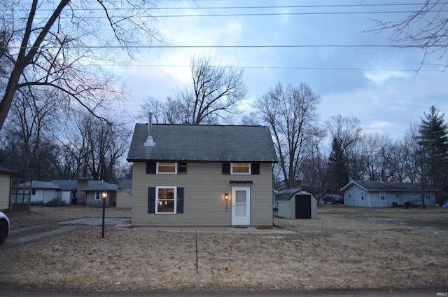 view of front of house with roof with shingles, an outdoor structure, and a storage shed