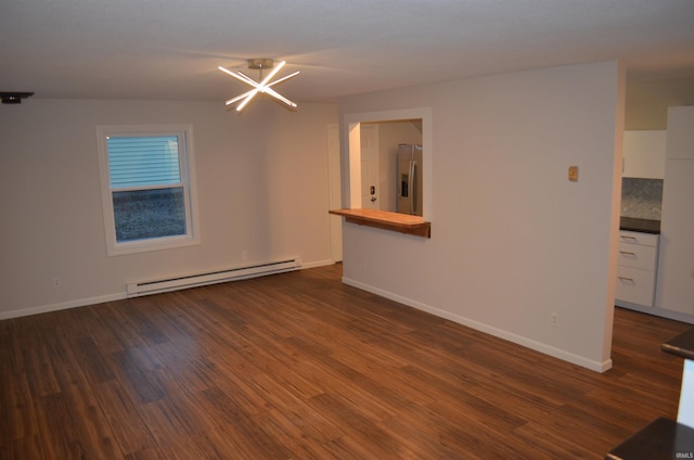 spare room featuring baseboards, baseboard heating, and wood finished floors