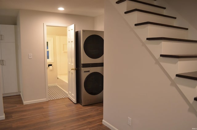 laundry area with recessed lighting, stacked washer and dryer, laundry area, wood finished floors, and baseboards