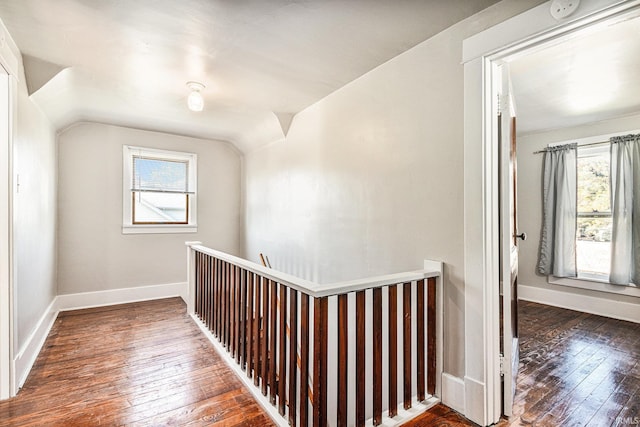 hallway with vaulted ceiling, hardwood / wood-style floors, an upstairs landing, and baseboards