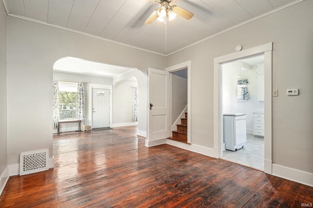 spare room with visible vents, arched walkways, baseboards, wood-type flooring, and ornamental molding