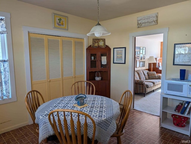 dining area featuring brick floor and baseboards