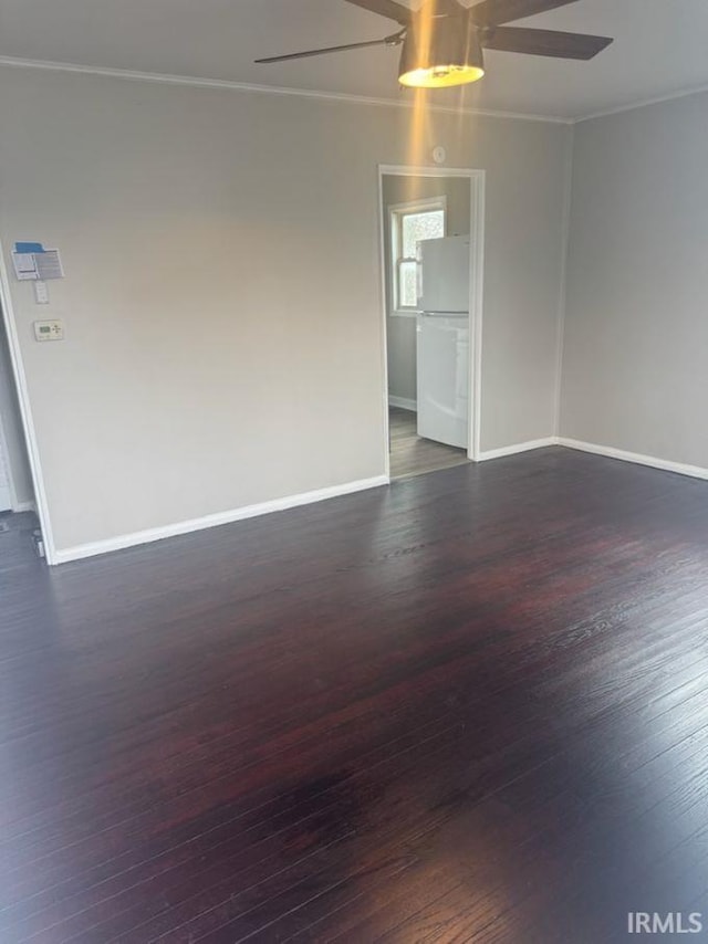 empty room with dark wood-style floors, ornamental molding, a ceiling fan, and baseboards