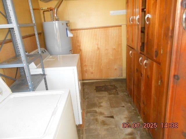 laundry room with a wainscoted wall, washer and clothes dryer, water heater, wood walls, and laundry area