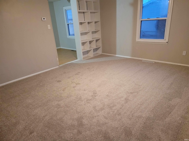 carpeted spare room with visible vents and baseboards