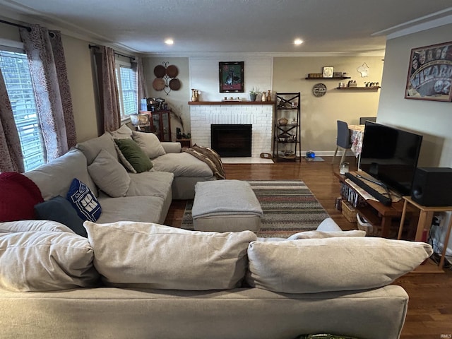 living area featuring ornamental molding, a brick fireplace, and wood finished floors