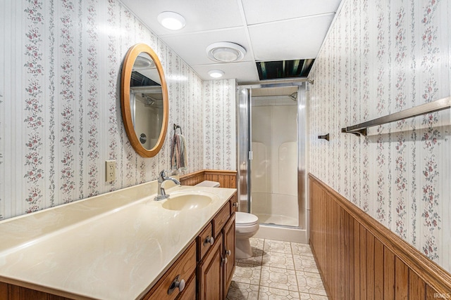 full bathroom featuring a wainscoted wall, toilet, a shower stall, tile patterned flooring, and wallpapered walls