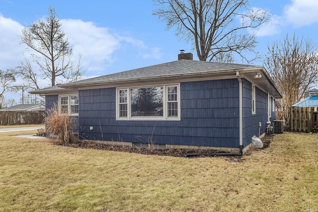 view of side of property with cooling unit, fence, a yard, roof with shingles, and a chimney