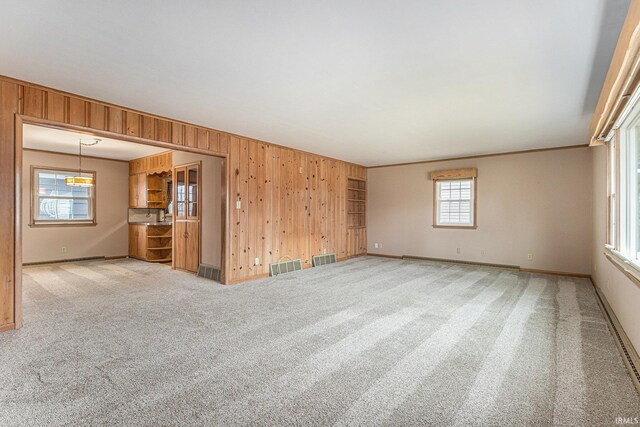 carpeted spare room featuring baseboards, visible vents, and wooden walls