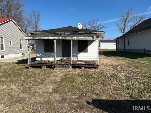 rear view of house featuring covered porch and a yard