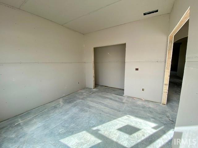 unfurnished bedroom with unfinished concrete floors, visible vents, and a closet