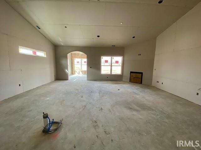 interior space featuring vaulted ceiling, arched walkways, and concrete flooring