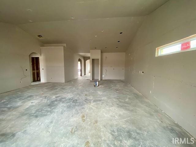 unfurnished room featuring visible vents, arched walkways, and concrete floors