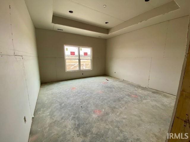 unfurnished room with unfinished concrete flooring and a tray ceiling